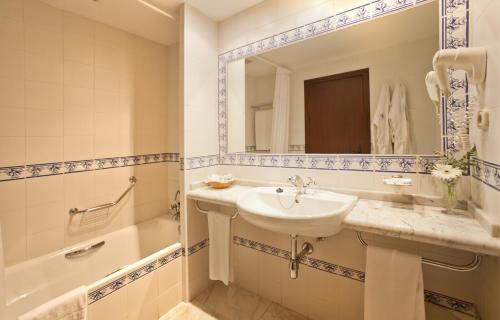uma casa de banho com um lavatório, uma banheira e um espelho. em TRH Mijas em Mijas