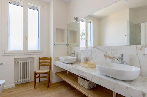 a white bathroom with two sinks and a chair at Villa sui Colli Bolognesi by Wonderful Italy in Bologna
