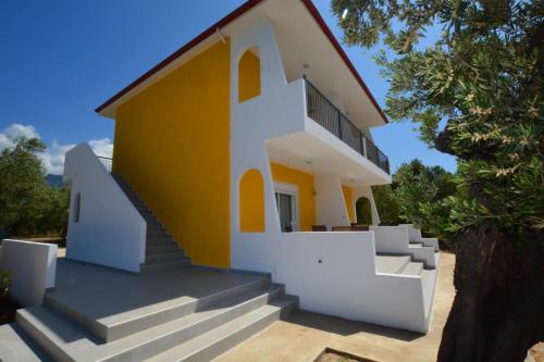 una casa de color amarillo y blanco en Platana Studios Karadolas en Skala Rachoniou