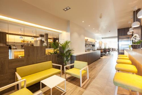 un restaurant avec des chaises jaunes et vertes et un comptoir dans l'établissement Hotel Les Mouettes, à Wenduine