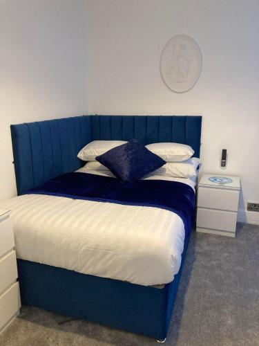 a bed with a blue headboard in a bedroom at The New Apollo Hotel in Blackpool