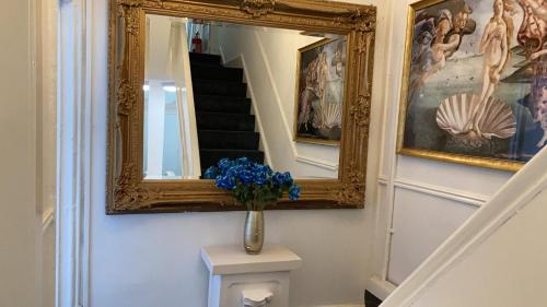 a vase of blue flowers on a toilet under a mirror at The New Apollo Hotel in Blackpool
