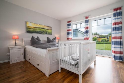 a white bedroom with a crib and windows at Ferienhaus Spiekeroog- Müritz in Zielow