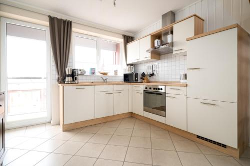 a kitchen with white cabinets and a large window at App Kapitänsdeck 415 am Müritzufer in Rechlin