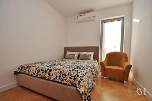 a bedroom with a bed and a chair and a window at DS Apartment in Dobrota