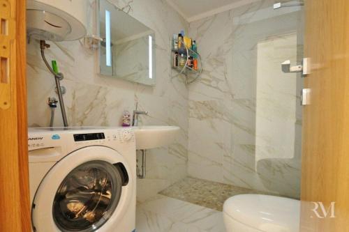 a bathroom with a washing machine and a sink at DS Apartment in Dobrota