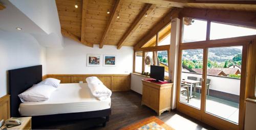 - une chambre avec un lit, un bureau et un balcon dans l'établissement Hotel Enzian, à Landeck