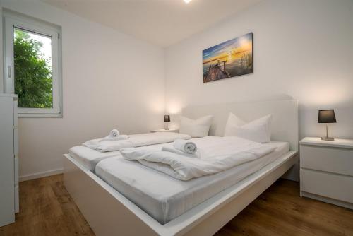 a large white bed in a white bedroom with a window at Ferienhaus Sternchen 2 in Schwarz