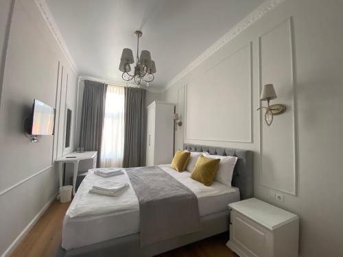 a white bedroom with a large bed with yellow pillows at Pensiunea Korona in Miercurea-Ciuc