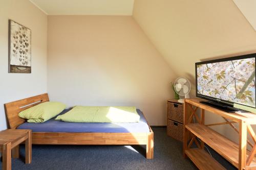 a bedroom with a bed and a flat screen tv at Vosskuhl Kabuff Twee in Südermarsch