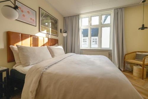 a bedroom with a large white bed and a window at Hotel Mayfair in Copenhagen