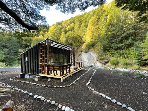 a tiny house sitting on a gravel road next to a mountain at Cabañas Los Huemules in Malalcahuello