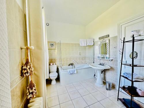 a bathroom with a sink and a toilet and a tub at Manoir de la Marjolaine in Cabourg