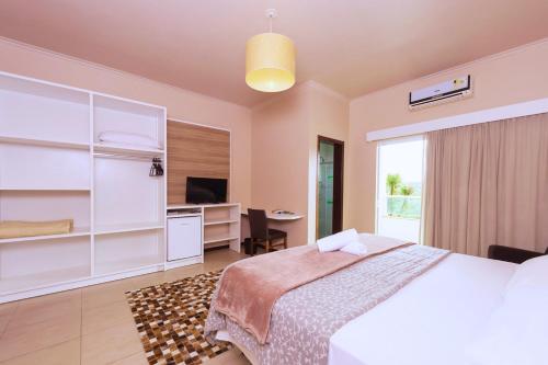 a bedroom with a bed and a desk and a television at Hotel Fazenda Dona Francisca in Joinville