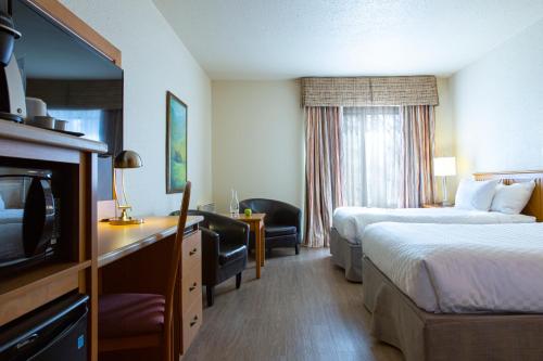 a hotel room with two beds and a flat screen tv at Hotel L'Oiseliere Montmagny in Montmagny