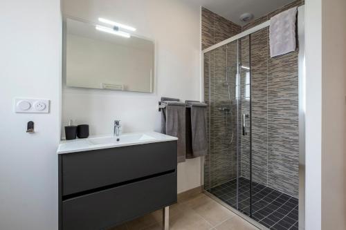 een badkamer met een wastafel en een douche bij L'Hirondelle Blanche - 4 étoiles in Dolus d'Oléron