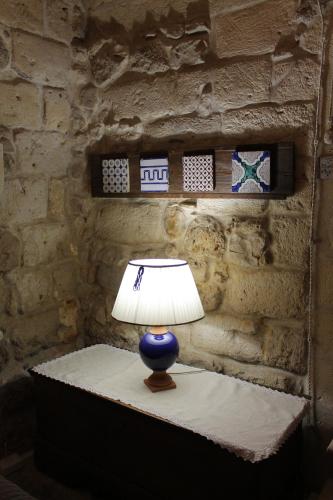 a lamp sitting on a table in front of a stone wall at Malta & Tufo in Altamura