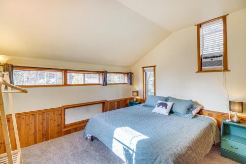 a bedroom with a blue bed and windows at Hungry Horse Cabin with Gas Grill, Near Glacier! in Hungry Horse