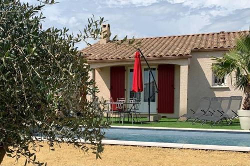 une maison avec une piscine et un parasol rouge dans l'établissement Villa sud de la France avec piscine privée, à Les Fumades-Les Bains