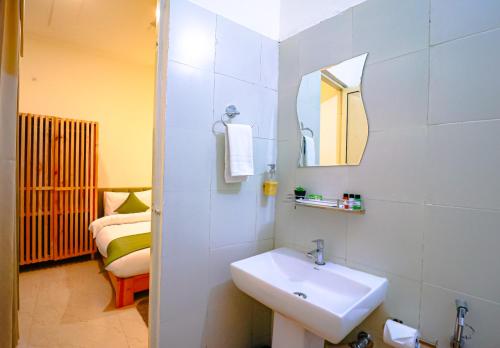 La salle de bains est pourvue d'un lavabo et d'un miroir. dans l'établissement Around Stays Hostel Rishikesh, Tapovan, à Rishikesh