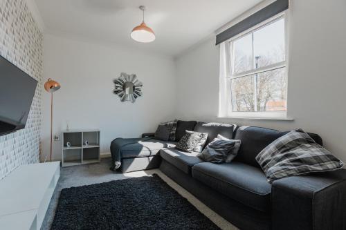 a living room with a couch and a window at Hullidays - Theatre Side Apartment - Refurbished 2023 in Hull