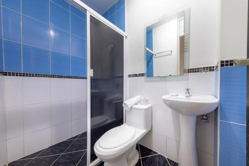 een badkamer met een wit toilet en een wastafel bij Hotel Confort Obelisk in Medellín