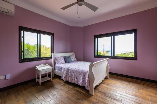 a purple bedroom with a bed and two windows at Villa Belle in Egmont