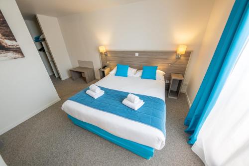 - une chambre avec un grand lit et des oreillers bleus dans l'établissement Hôtel Saint Laurent, à Nogent-sur-Seine