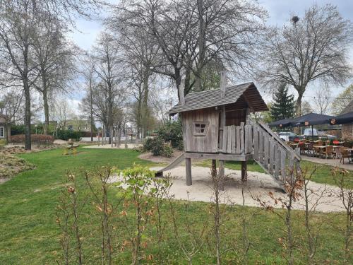 a wooden play house on a slide in a park at Chalet Panorama near Efteling - with garden and swimmingpool Europarcs in Kaatsheuvel