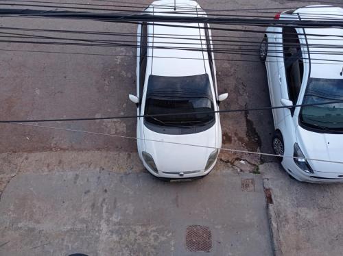 two white cars parked in a parking lot at APTO COM VARANDA - 5KM DO AEROPORTO BSB - Nucleo Bandeirante in Brasília