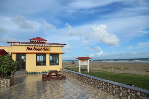 aeat burrito cafe with a bench in front of the beach at Sher Bengal Beach Resort in Mandarmoni