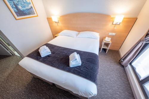 a hotel room with a large bed with two bags on it at Hôtel Saint Laurent in Nogent-sur-Seine