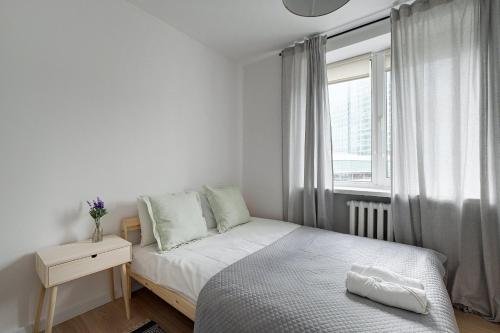 a small white bedroom with a bed and a window at Urban Oasis Private Apartment with Palace of Culture View in Warsaw