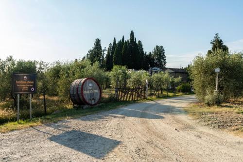 a dirt road with a sign and a barrel on the side at Tenuta Poggio ai Mandorli in Greve in Chianti