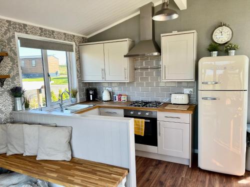 a kitchen with white cabinets and a white refrigerator at Brackenrigg Lodge in Felton