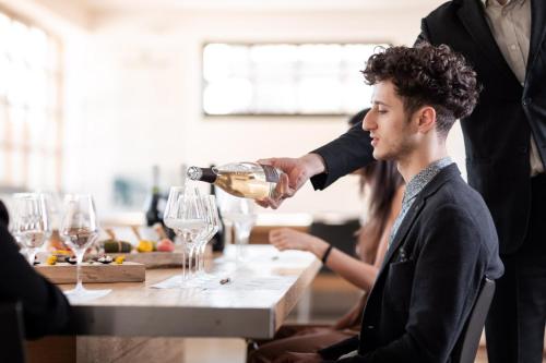a man pouring a glass of wine at a table at Casa dell'Artista in Valdobbiadene