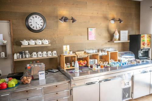 a kitchen with a counter with a clock on the wall at H&ocirc;tel Saint Laurent in Nogent-sur-Seine
