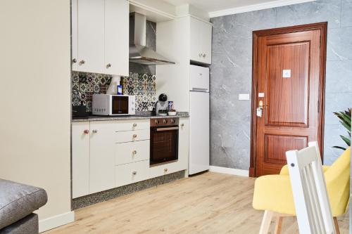 a kitchen with white cabinets and a microwave at Padrón Suites in Padrón