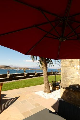 a red umbrella sitting on a patio with a palm tree at Dungallan Country House Bed & Breakfast in Oban