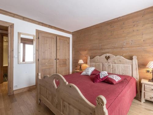 - une chambre avec un grand lit en bois et des draps rouges dans l'établissement Appartement élégant avec wifi, terrasse et parking couvert à Val-d'Isère, proche des pistes - FR-1-694-100, à Val dʼIsère
