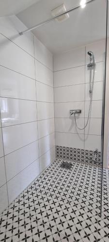 a bathroom with a shower and a black and white tiled floor at Apartament Przystań in Frombork