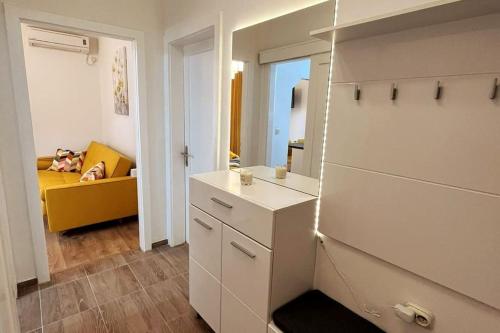 een witte keuken met een gele bank in een kamer bij Lijepo uređen stan u centru grada in Knin