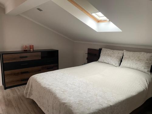 1 dormitorio con cama blanca y tragaluz en Infinity Home Apartman, en Hévíz