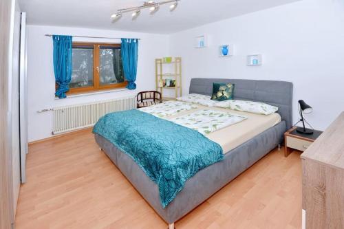 a bedroom with a large bed with a blue blanket at Ferienwohnung Karawankenblick in Bach