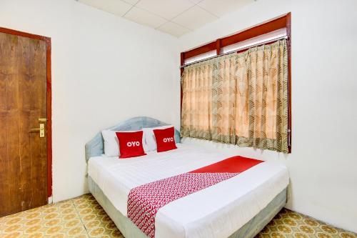 een slaapkamer met een bed met rode kussens en een raam bij OYO 92505 Asta Guesthouse in Yogyakarta