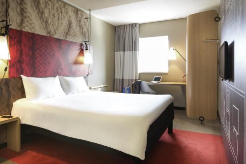 a hotel room with a large white bed and a desk at Hotel ibis Rennes Centre Gare Sud in Rennes