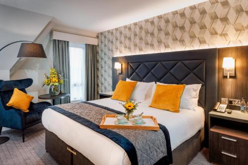 Camden Court Hotel في دبلن: غرفة فندق بسرير كبير مع مخدات صفراء