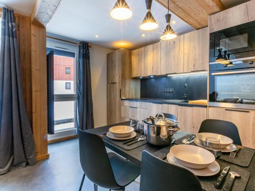 une salle à manger avec une table et des chaises et une cuisine dans l'établissement Appartement rénové 2022 avec wifi, balcon sud, 5 pers, équipements famille, proche commodités - FR-1-694-294, à Val dʼIsère
