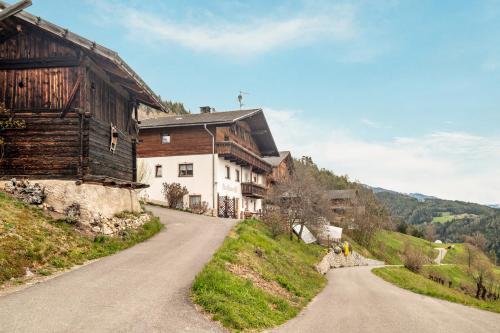a house on a hill next to a dirt road at Stöcklhuberhof in Vandoies
