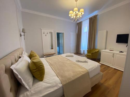 a bedroom with a large white bed and a chandelier at Pensiunea Korona in Miercurea-Ciuc